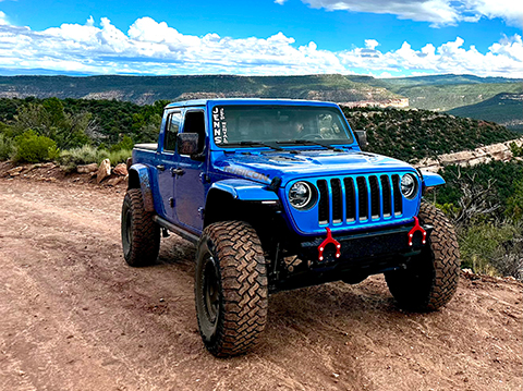 Front view of a blue Jeep Gladiator with red hooks on the front